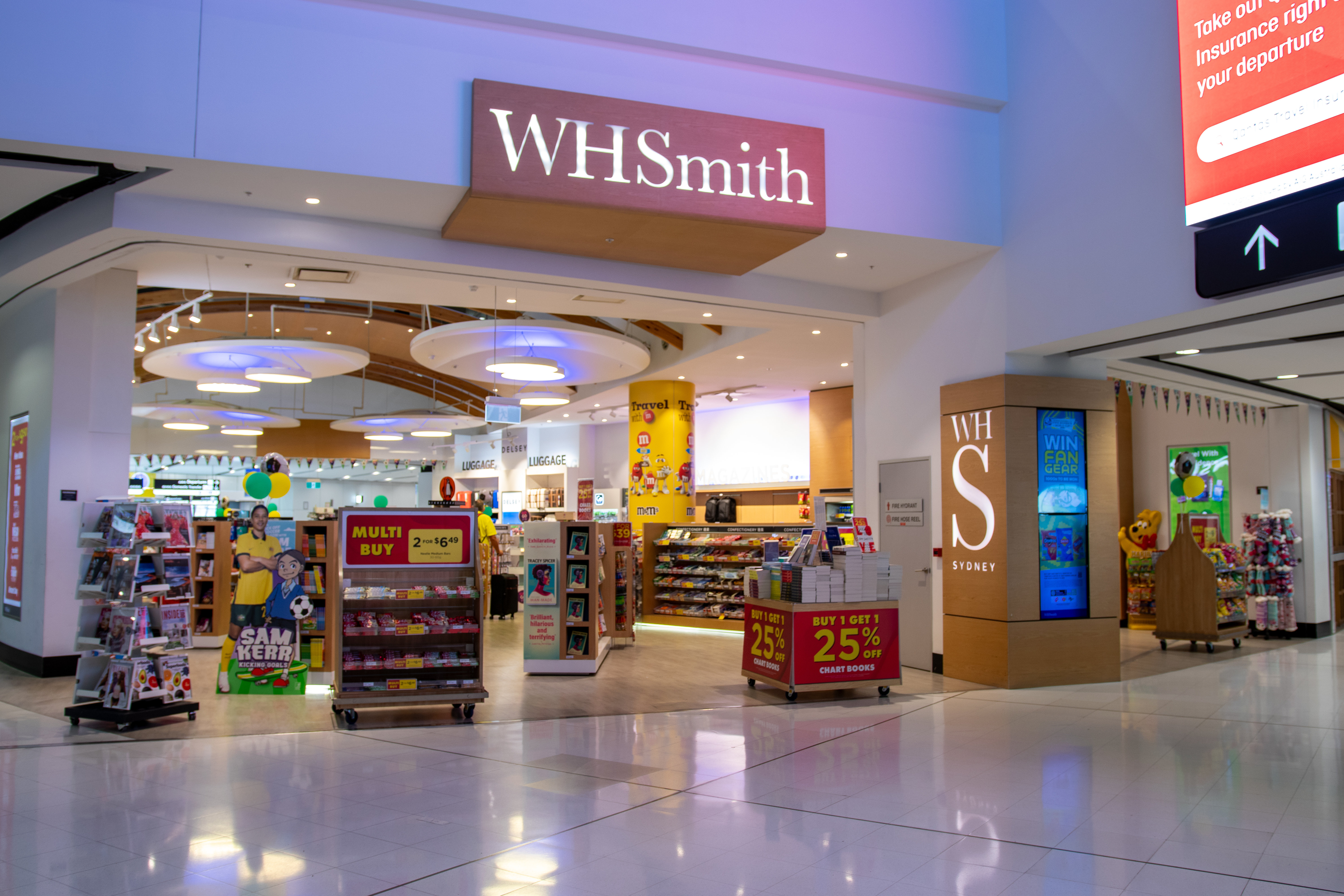Entrance of a WHSmith store with books, magazines, and promotional displays at the front.