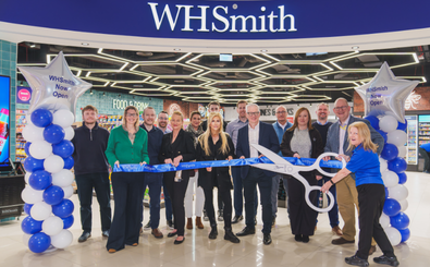 Group of people standing in front of a WHSmith entrance during a ribbon‑cutting event.